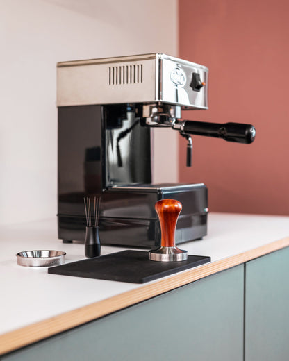Houten tamper op een werkblad bij een espressomachine