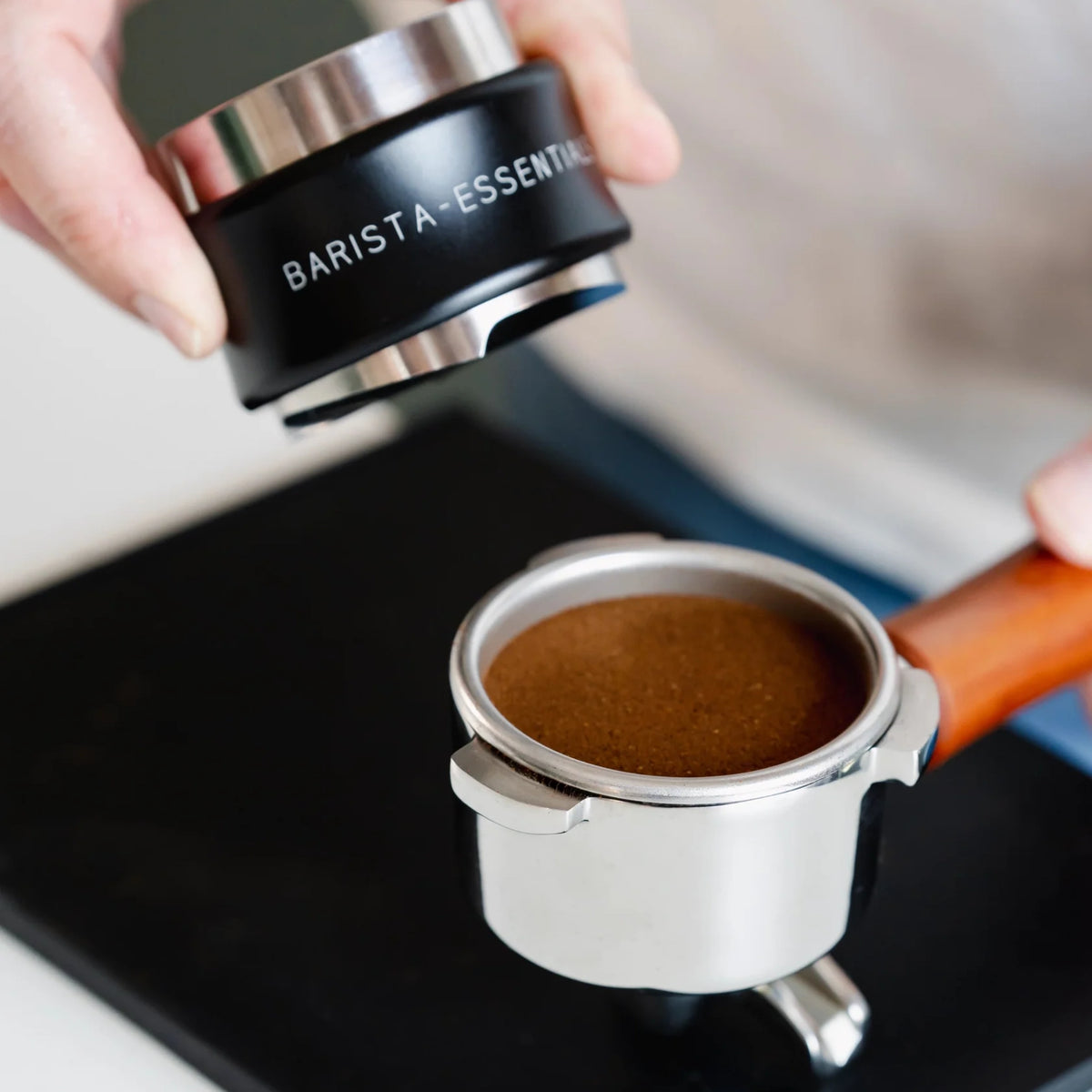 Zwarte combinatietool boven een vlak getampte koffiepuck