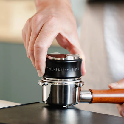 Een zwarte tamper en verdeler wordt op een portafilter gebruikt