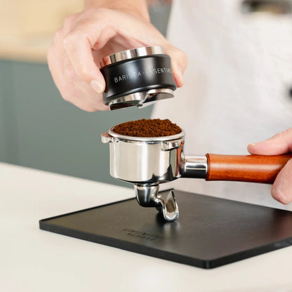 Zwarte verdeelzijde boven gemalen koffie in een portafilter