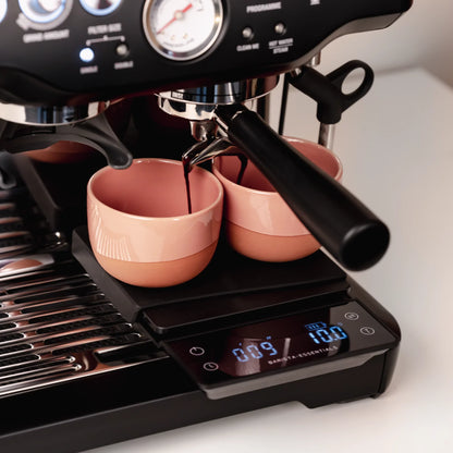 Twee roze kopjes op een koffieweegschaal tijdens espresso zetten