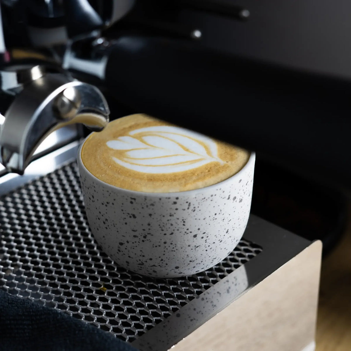 Latte kopje met latte art onder piston – barista-proof en klaar om cadeau te geven.