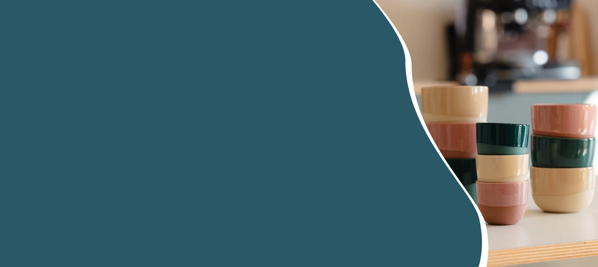 Latte, cappuccino en espresso kopjes van 250 ml, 180 ml en 60 ml in verschillende kleuren naast een espressomachine voor koffiedranken, espresso en latte art thuis.