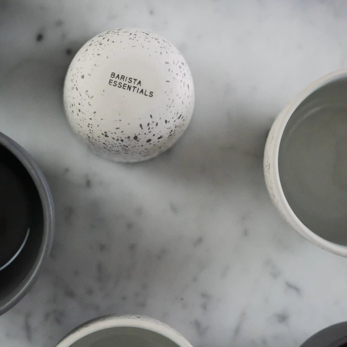 Onderkant van latte kopje met Barista Essentials logo – onderdeel van oefenserie voor thuisbarista’s.