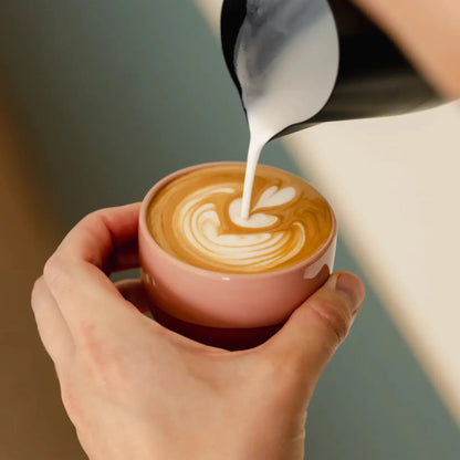 Melk wordt in een roze kopje geschonken voor latte art