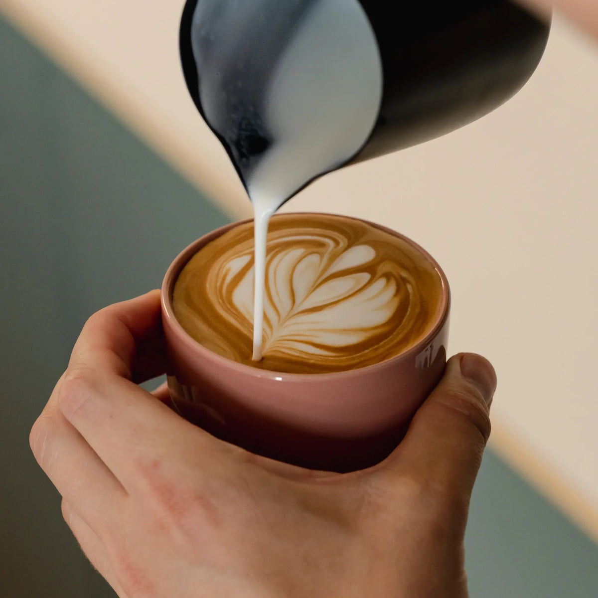 Melk wordt in een roze kopje geschonken voor latte art