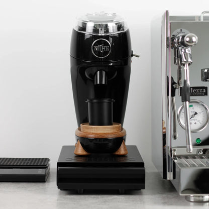 Koffiemolen op een zwarte uitkloplade naast een espressomachine
