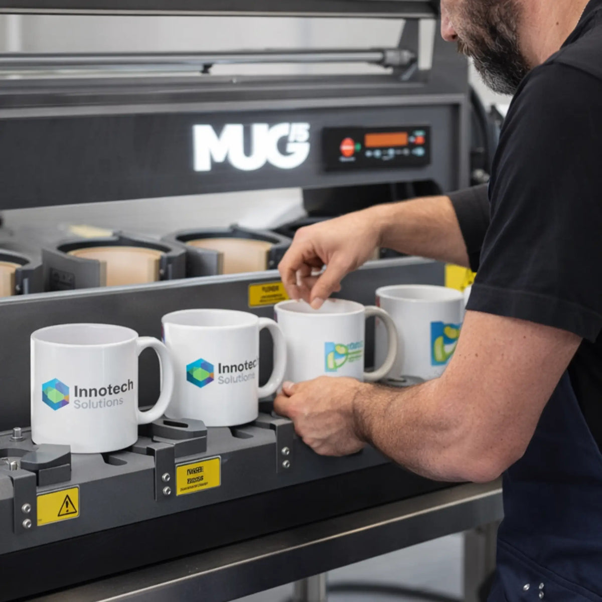 Medewerker plaatst gepersonaliseerde mokken in een MUG15 sublimatiepers voor zakelijke productie bij De Barista Shop