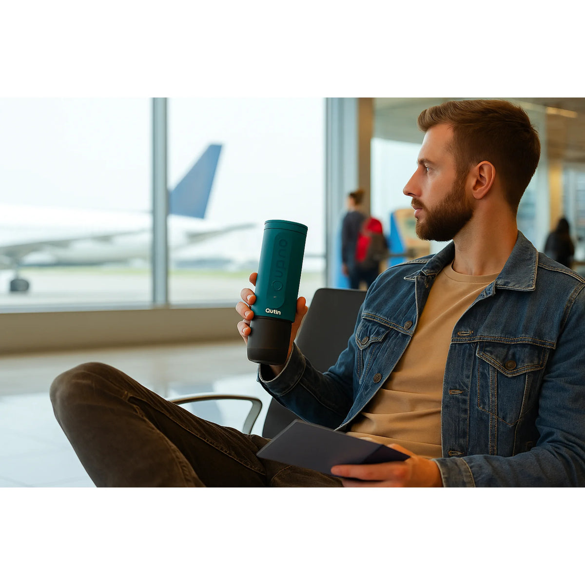 Reiziger in luchthavenlounge met een OutIn Nano koffiemaker in de hand, wachtend op zijn vlucht.