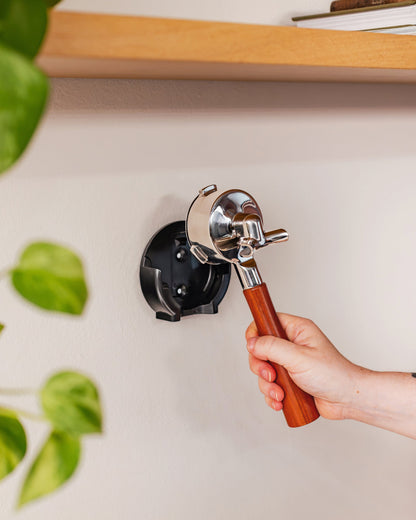 Een hand plaatst een portafilter in de 58 mm wandhouder