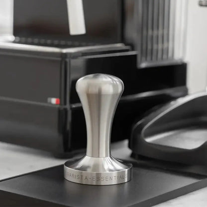 RVS tamper naast een espressomachine