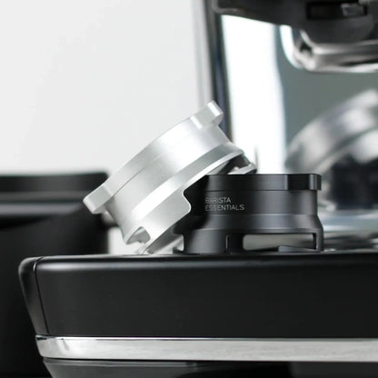 Zwarte en zilveren doseerring naast elkaar op de lekbak van een espressomachine