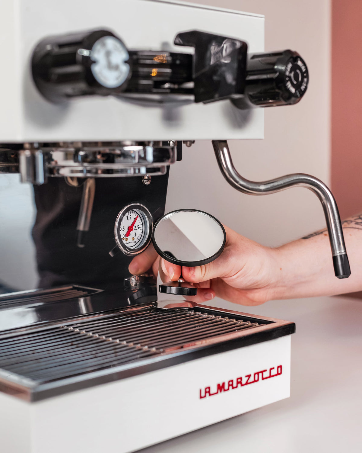 Hand stelt de extractiespiegel op de lekbak van een espressomachine af