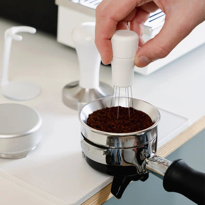 Koffie wordt aangedrukt met een witte tamper boven een witte mat