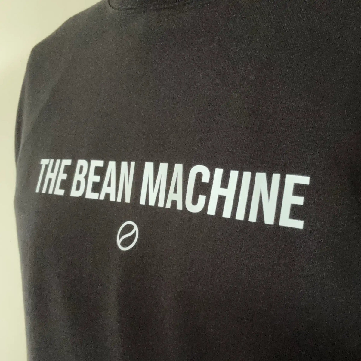 Close-up van The Bean Machine koffiesweater met duidelijke print en glad katoen – ideaal voor barista's en koffie-enthousiastelingen.