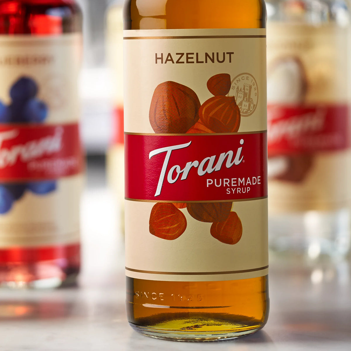 Close-up van Torani Puremade Hazelnoot Siroop 750ml fles en ingrediënten.
