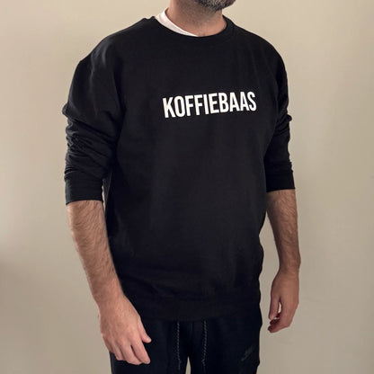 Comfortabele zwarte sweater met “KOFFIEBAAS” tekst – gedragen door model