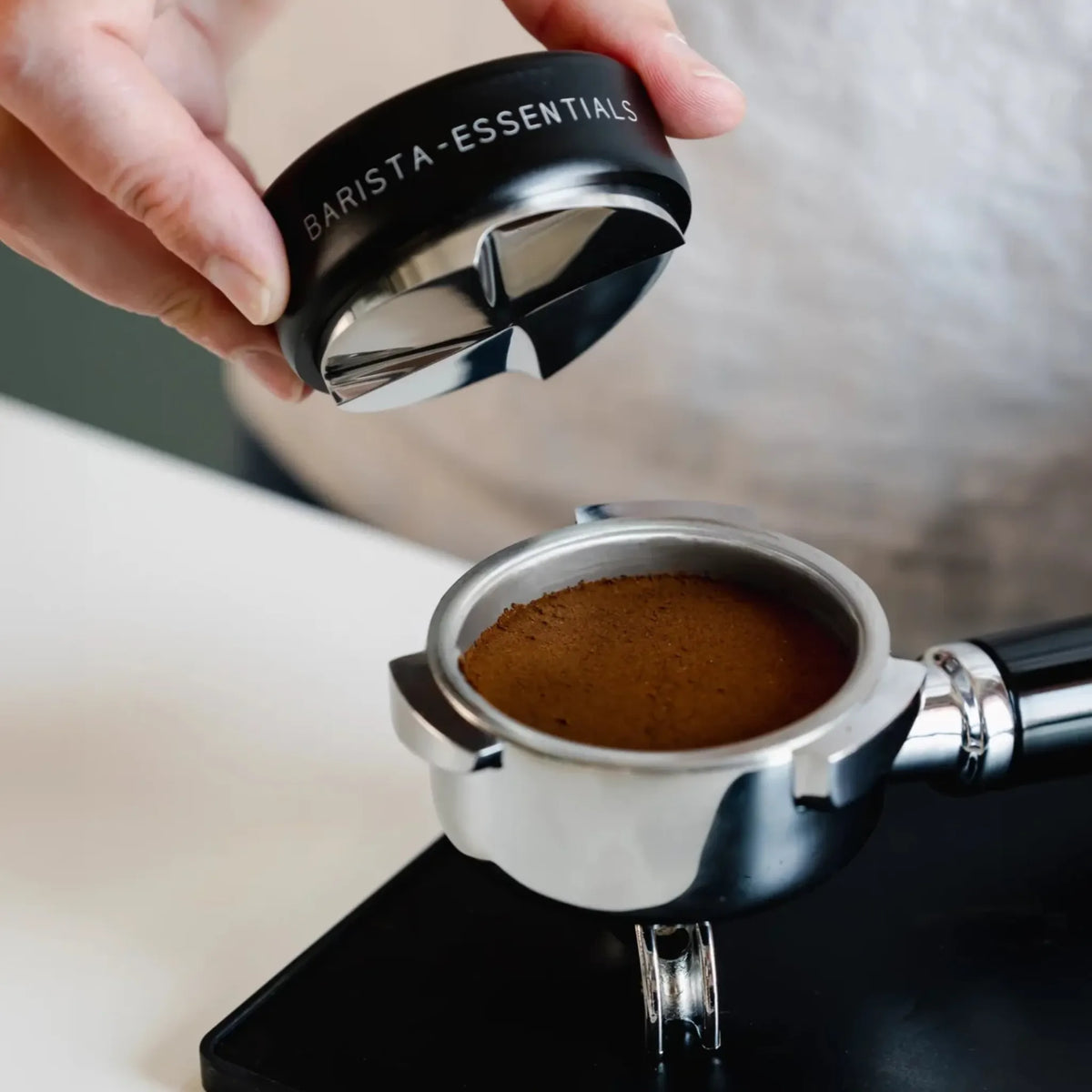 Zwarte koffieverdeler boven een egaal verdeeld koffiebed