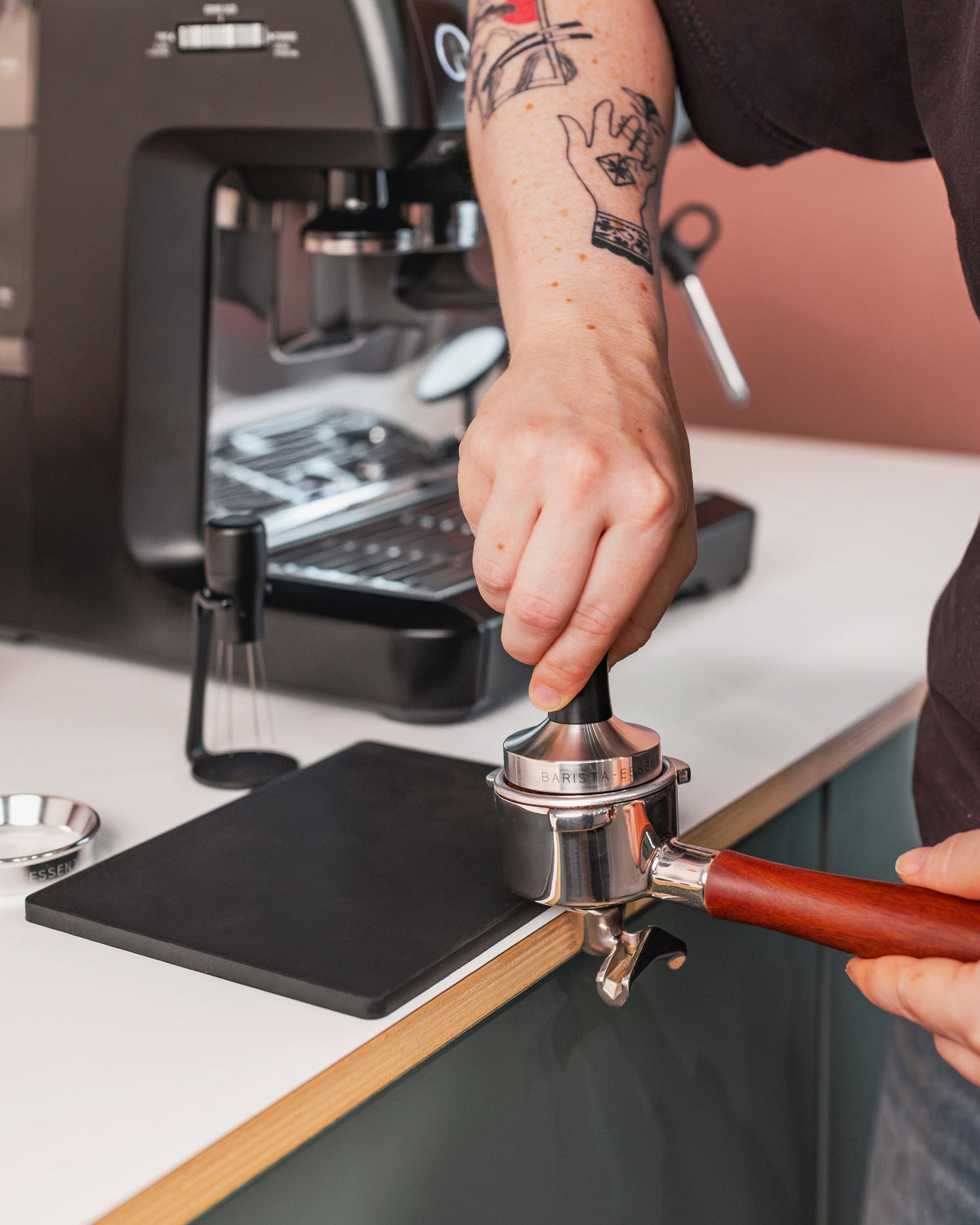 Zwarte tamper in een filterbakje bij het voorbereiden van espresso
